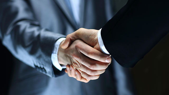 Handshake – Hand holding on black background Two Males Handshake header image