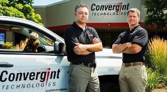 2 colleagues stand outside of Convergint Technology Vehicle with Gopher in front seat