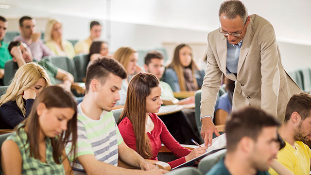 Teacher assisting female student in the classroom header image