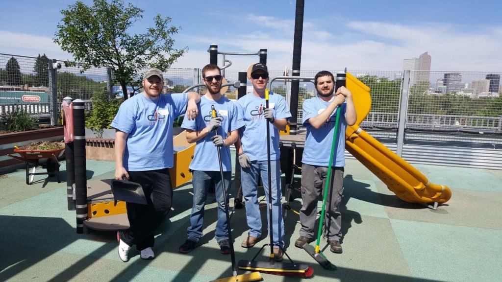 Colleagues holding brooms at Convergint day 2017