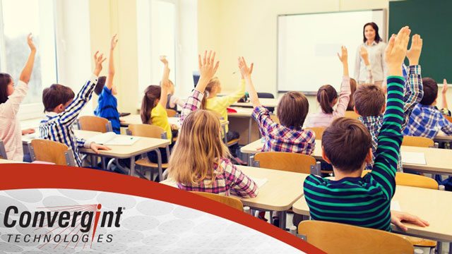 Children in classroom raising hands