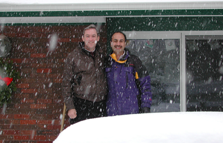 Two men standing in front of a house with snow