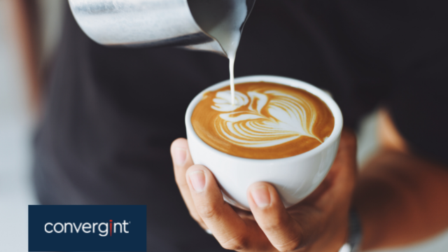 Man pouring milk into a coffee to create latte art