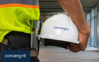 Male engineer holding hard hat by his side