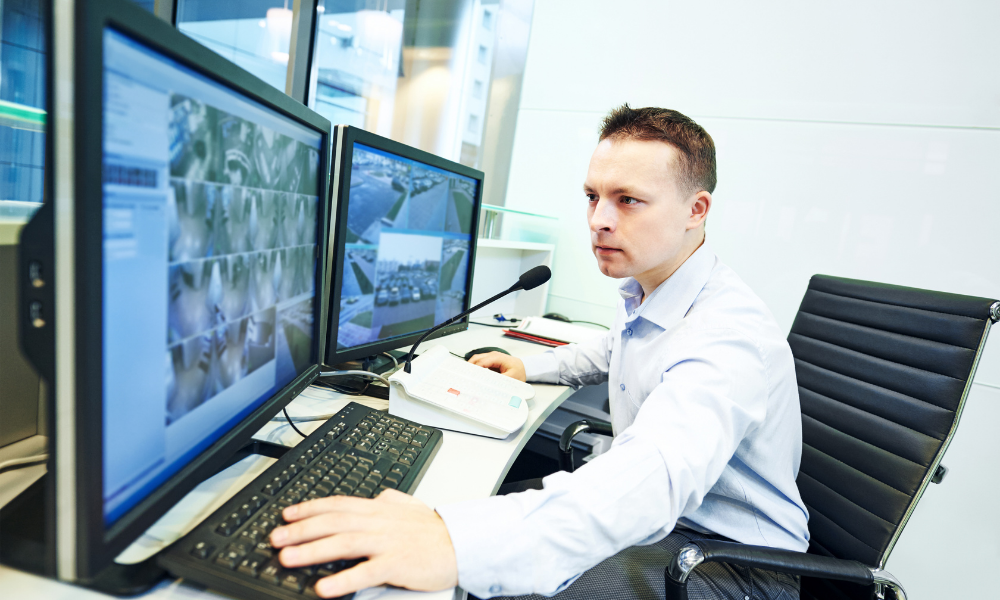 Security man watching monitors and communicating through microphone