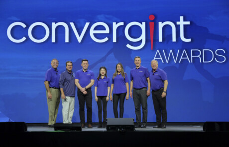 Seven people smiling on stage for a picture