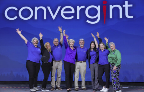 Eight people on stage with their hands in the air