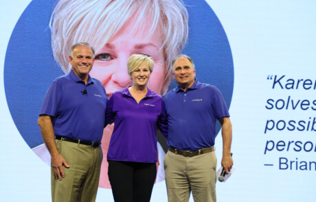 Three people smiling on stage