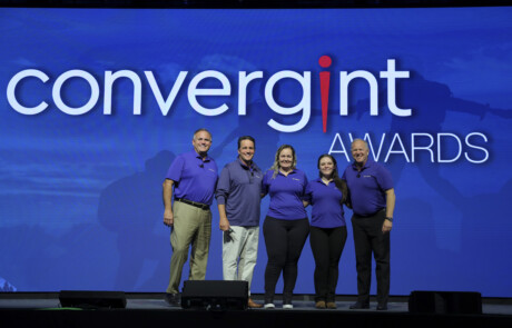 Five people smiling for a picture on stage