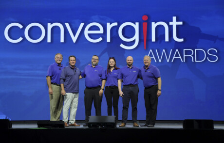 Six people smiling for a picture on stage