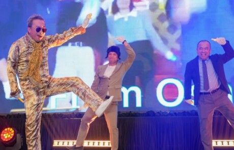 Eight people on stage with their hands in the air