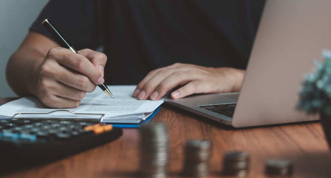 A person holding a pen and writing on a paper
