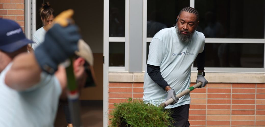 Man shoveling grass while others landscape around him.