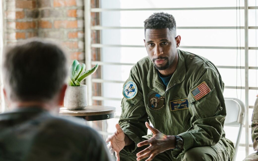 Person sitting in chair dressed in army outfit talking to someone across from them
