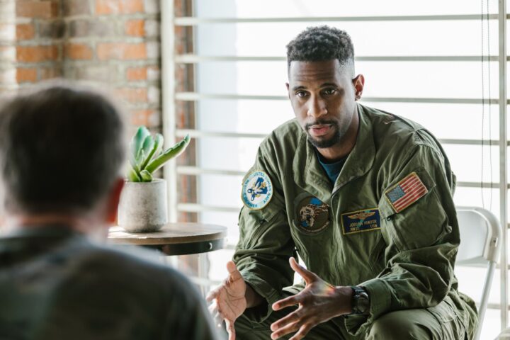 Person sitting in chair dressed in army outfit talking to someone across from them
