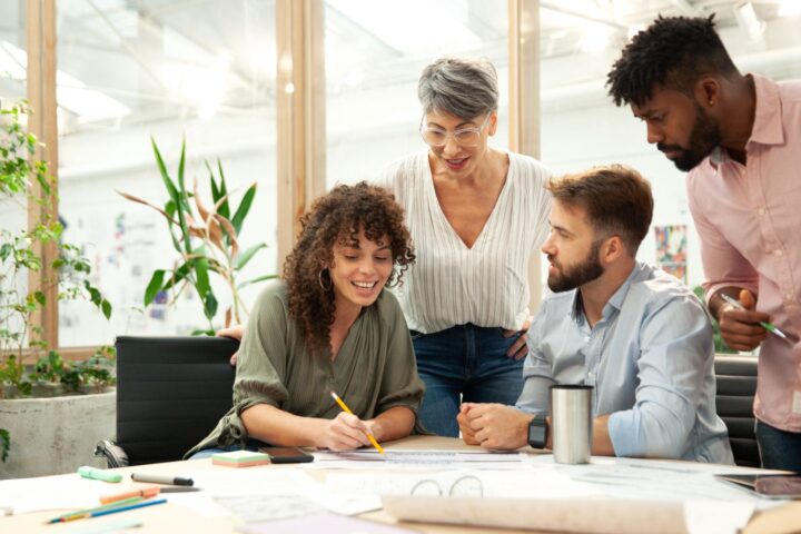 A group of people around a table smiling and looking at papers