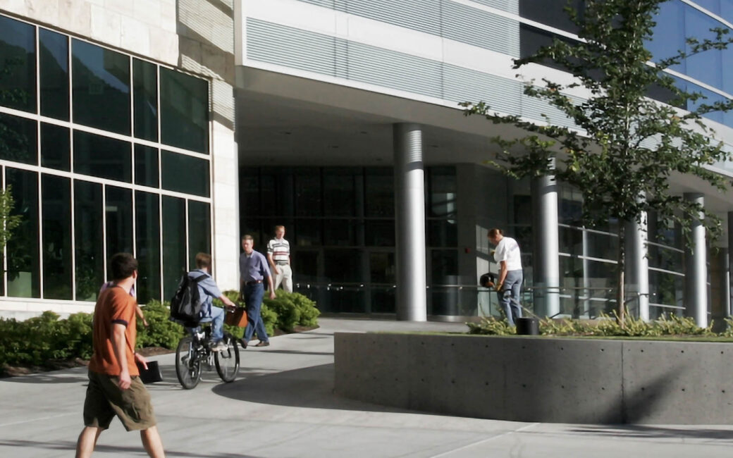 pedestrians walk by a modern building of a company